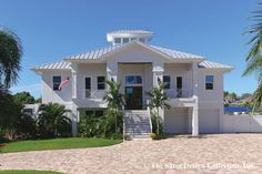 a large white house with palm trees in the front yard and stairs leading up to it