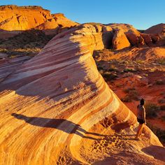 a person standing on top of a large rock formation in the middle of an arid area