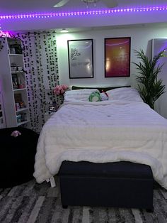 a white bed sitting in a bedroom next to a window with purple lights on it