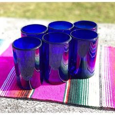 six blue glass cups sitting on top of a colorful towel