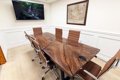 a conference room with a large wooden table and brown leather chairs in front of a flat screen tv