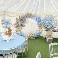 a teddy bear sitting on top of a blue table in a room filled with balloons