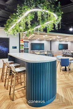 the interior of an office with plants hanging from the ceiling and bar stools in front of it