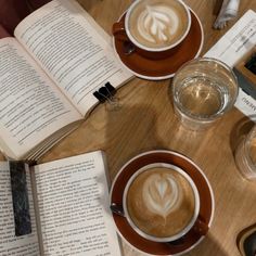 two cups of coffee and an open book on a table