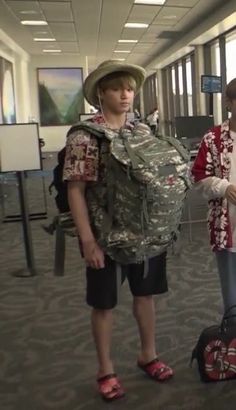 two young men standing next to each other in an airport with luggage on the ground