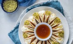 a white plate topped with lots of food next to a bowl of dipping sauce on top of it