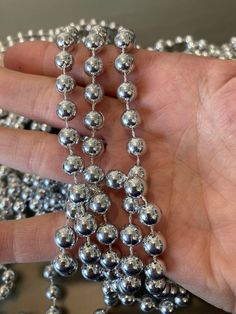 a hand is holding a bunch of silver balls