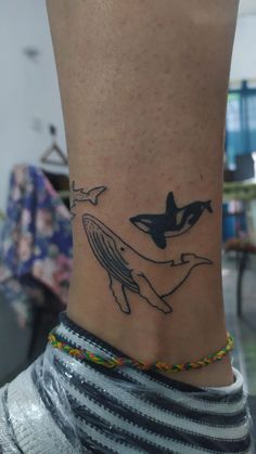 a tattoo on the ankle of a woman with an orca whale in it's stomach