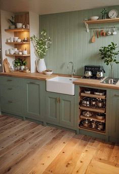 a kitchen filled with lots of green cabinets and wooden flooring next to a white stove top oven