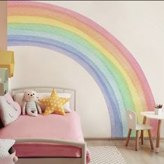 a child's bedroom decorated in pastel colors with a rainbow painted on the wall