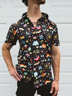 Elevate your wardrobe to new galaxies with our Cosmic Button-Up Shirt! This shirt is a vibrant celebration of all things cosmic, featuring an eye-catching pattern that includes planets, rainbows, stars, UFOs, and more. Perfect for anyone looking to make a stellar fashion statement. **Key Features - **Unique Design This shirt boasts a bold, colorful space-themed print that is sure to turn heads. The pattern includes a mix of celestial bodies, rainbows, and whimsical elements, making it a true conversation starter. - **Premium Fabric Made from high-quality, breathable recycled fabric, this shirt ensures comfort and durability. Ideal for casual outings, festivals, and themed parties. - **Versatile Style With its classic button-up design, this shirt can be dressed up or down. Pair it with jean Fun Black Summer Shirt, Unisex Short Sleeve Summer Shirt, Multicolor Shirt For Summer Festival, Unisex Tops For Summer Music Festival, Cotton Shirt With Star Print For Summer, Groovy Graphic Print Summer Shirt, Hippie Graphic Print Shirt For Summer, Summer Hippie Printed Shirt, Casual Button-up Festival Shirt