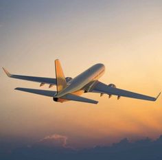 an airplane is flying in the sky at sunset