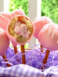 three candy candies with pink frosting on them sitting in purple plastic wrappers