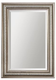 an ornate silver framed mirror on a white wall with beading around the edges and sides