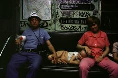 a man and two women sitting on a bench with a baby in their lap next to them