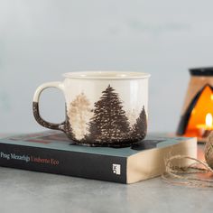 a coffee cup sitting on top of a book next to a candle and some string