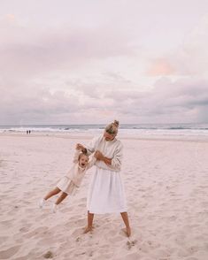 a mother and daughter playing on the beach