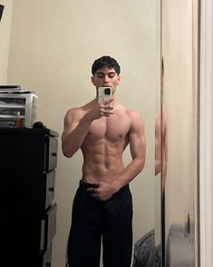 a shirtless man taking a selfie in front of a mirror with his cell phone