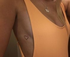 a woman with a small heart tattoo on her left arm and right arm behind her back