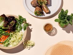 an overhead view of some food on a white plate and two bowls with sauces