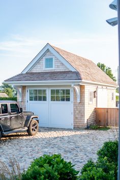 a black truck parked in front of a house with a white garage door and windows