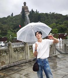 a man holding an umbrella in front of a statue