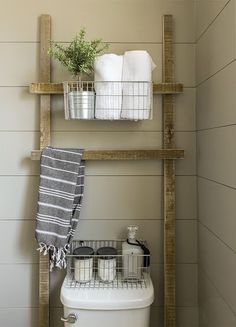 a white toilet sitting next to a wooden shelf filled with towels and other bathroom items