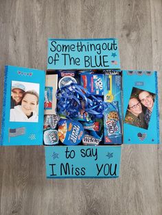 a blue box filled with candy and candies on top of a wooden floor next to two pictures