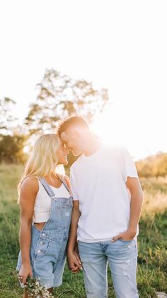 a man and woman standing next to each other in the middle of a grass field