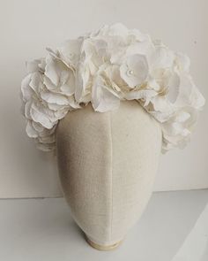 a white flowered headpiece on a mannequin's head is shown