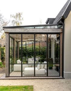 a living room with glass walls and furniture in the middle of an outdoor patio area