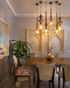 a dining room table and chairs with lights hanging from the ceiling