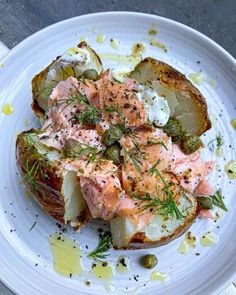 a white plate topped with potatoes covered in smoked salmon and dill garnish