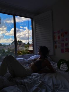 a woman laying on top of a bed in a bedroom next to a large window