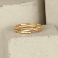 a gold ring sitting on top of a block of white concrete, with the end of it's band curled up