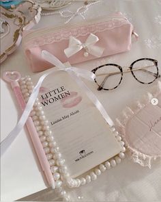 a pair of glasses sitting on top of a table next to a book and some pearls