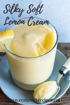 a glass cup filled with lemon cream on top of a plate next to a spoon