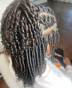 the back of a woman's head with long, curly hair and twists in it