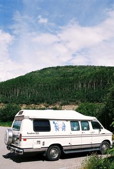 a white van parked in front of a lush green hillside