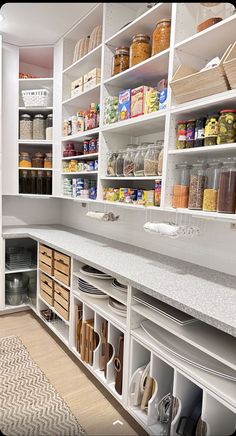 an organized pantry with white cabinets and drawers