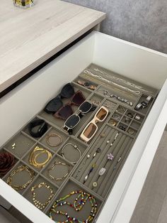 an open drawer with many pairs of sunglasses and bracelets in it on top of a counter