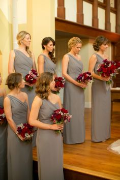 a group of women standing next to each other in front of a mirror holding bouquets