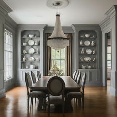 a dinning room table and chairs in front of a bookcase with china on it