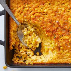 a casserole dish with corn on top and a spoon in the casserole