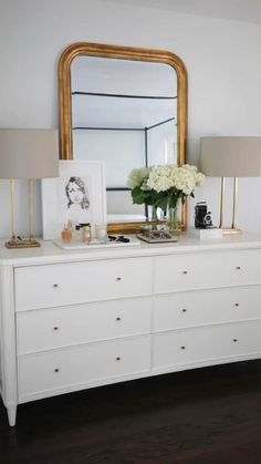 a white dresser with flowers and pictures on it