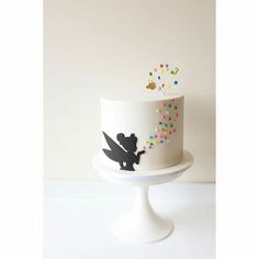 a white cake with black silhouettes and colorful sprinkles on the top