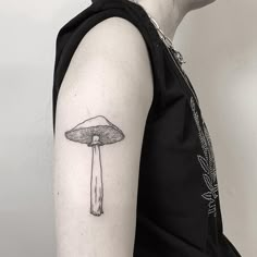 a mushroom tattoo on the left upper arm and back of the right arm is black and white