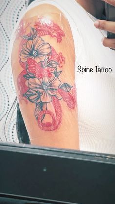 a woman's arm with flowers and a snake tattoo on it, in front of a mirror