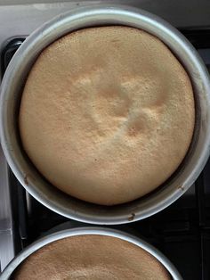 two pans filled with cake sitting on top of a stove