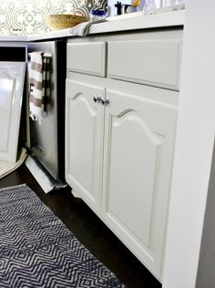 a kitchen with white cabinets and blue rug